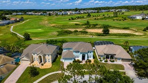 A residential area with houses, a golf course, and solar panels. - King's Way Haven - 7BR Golf-view Home With Pool and Game Room (Davenport)