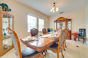 A dining room with a wooden table, chairs, and a chandelier. - King's Way Haven - 7BR Golf-view Home With Pool and Game Room (Davenport)