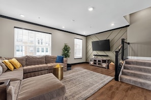 Ein modernes Wohnzimmer mit einer Couch, einem Couchtisch, einem Fernseher und einer Treppe.