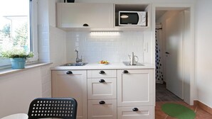 A compact kitchen with a microwave, sink, and cabinets.