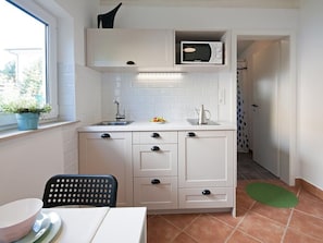 A compact kitchen with a microwave, sink, and cabinets.