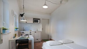 A compact bedroom with a single bed and a small kitchenette.
