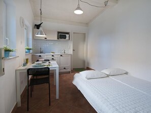 A compact bedroom with a single bed and a small kitchenette.