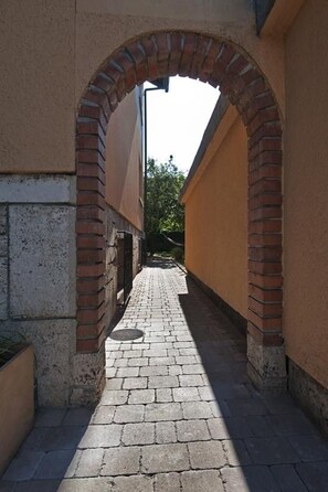 A narrow alleyway with a brick archway leading to a building.