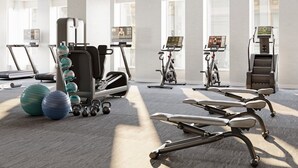 A modern gym with exercise equipment, a treadmill, and large windows.