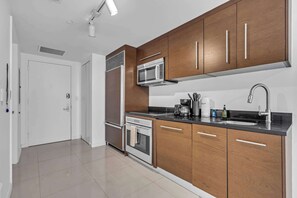 Eine moderne Küche mit Holzschränken, Edelstahlgeräten und einer schwarzen Arbeitsplatte.