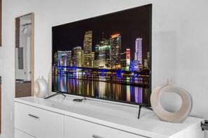 Ein Flachbildfernseher an einem weißen Schrank, ergänzt durch zwei dekorative Vasen.