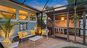 A covered outdoor patio with metal furniture, a small table, and potted plants. - Tropical Oasis in Seminole Heights (Tampa)