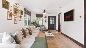 A living room with a sofa, coffee table, and a TV mounted on the wall. - Tropical Oasis in Seminole Heights (Tampa)