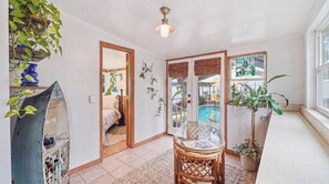 A room with a bed, a glass table, a potted plant, a view of a pool, and a ceiling fan. - Tropical Oasis in Seminole Heights (Tampa)