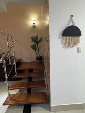A staircase with wooden steps and metal railings, a potted plant, a wall-mounted light fixture, and a hanging decorative item. - Villa with a private pool in Punta Cana (Punta Cana)