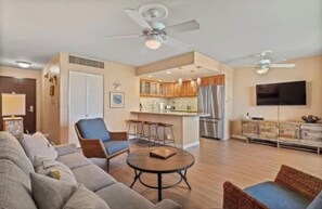 A spacious living room with a sofa, a round coffee table, and a dining area with bar stools. - HUGE SALE!! OCEAN FRONT and BEACH FRONT . Ground floor just steps from the Ocean (Kihei)