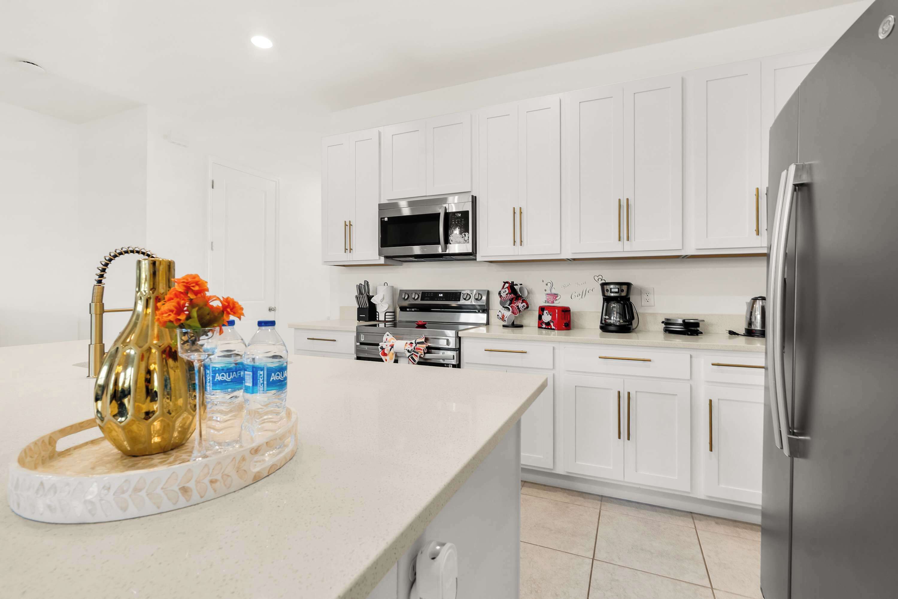 A modern kitchen with white cabinetry, stainless steel appliances, and a marble countertop.