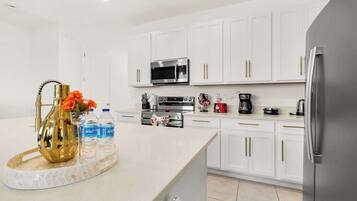 A modern kitchen with white cabinetry, stainless steel appliances, and a marble countertop.
