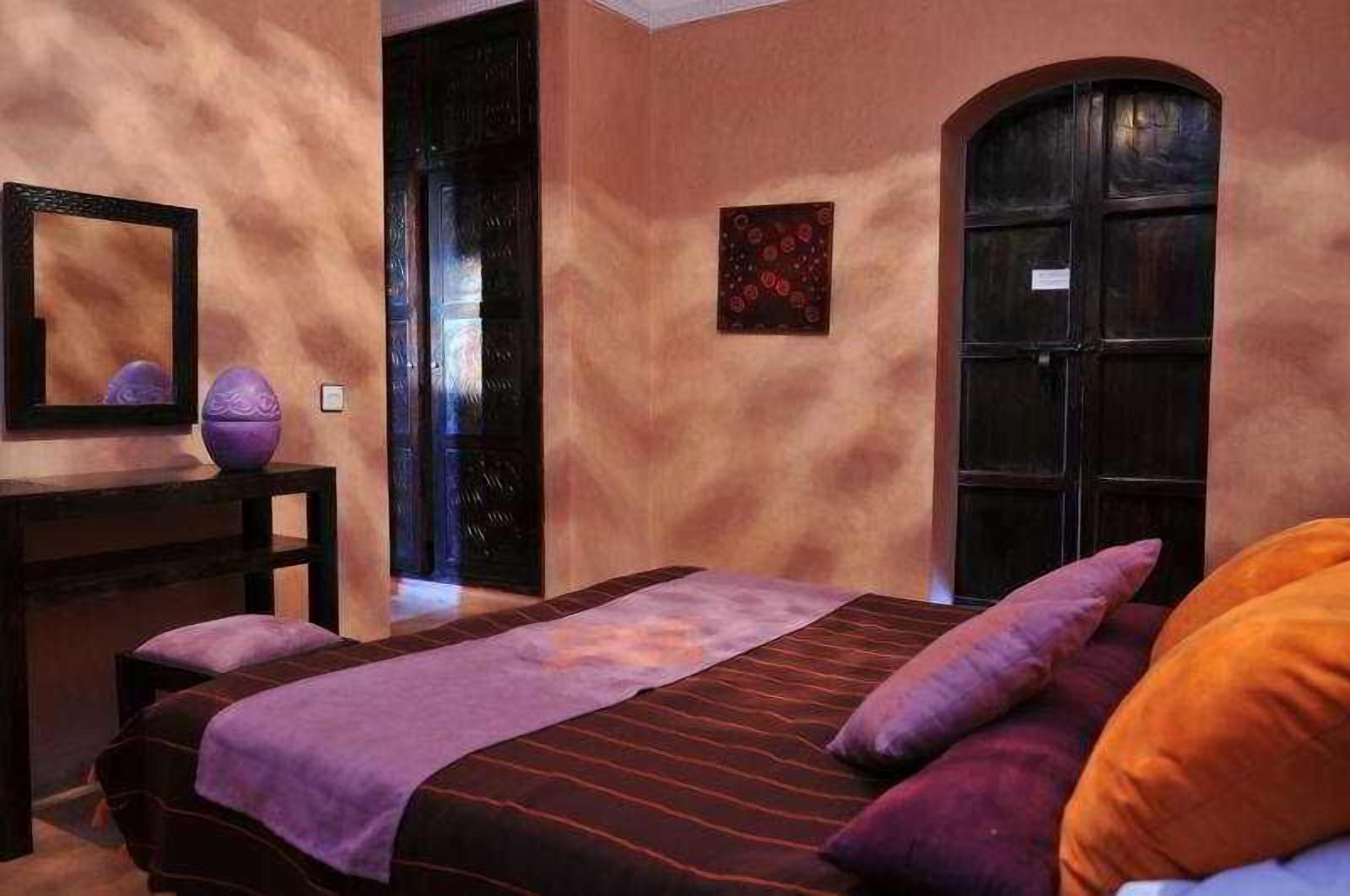 Une chambre à coucher avec un lit, une table de chevet, un miroir et une porte.