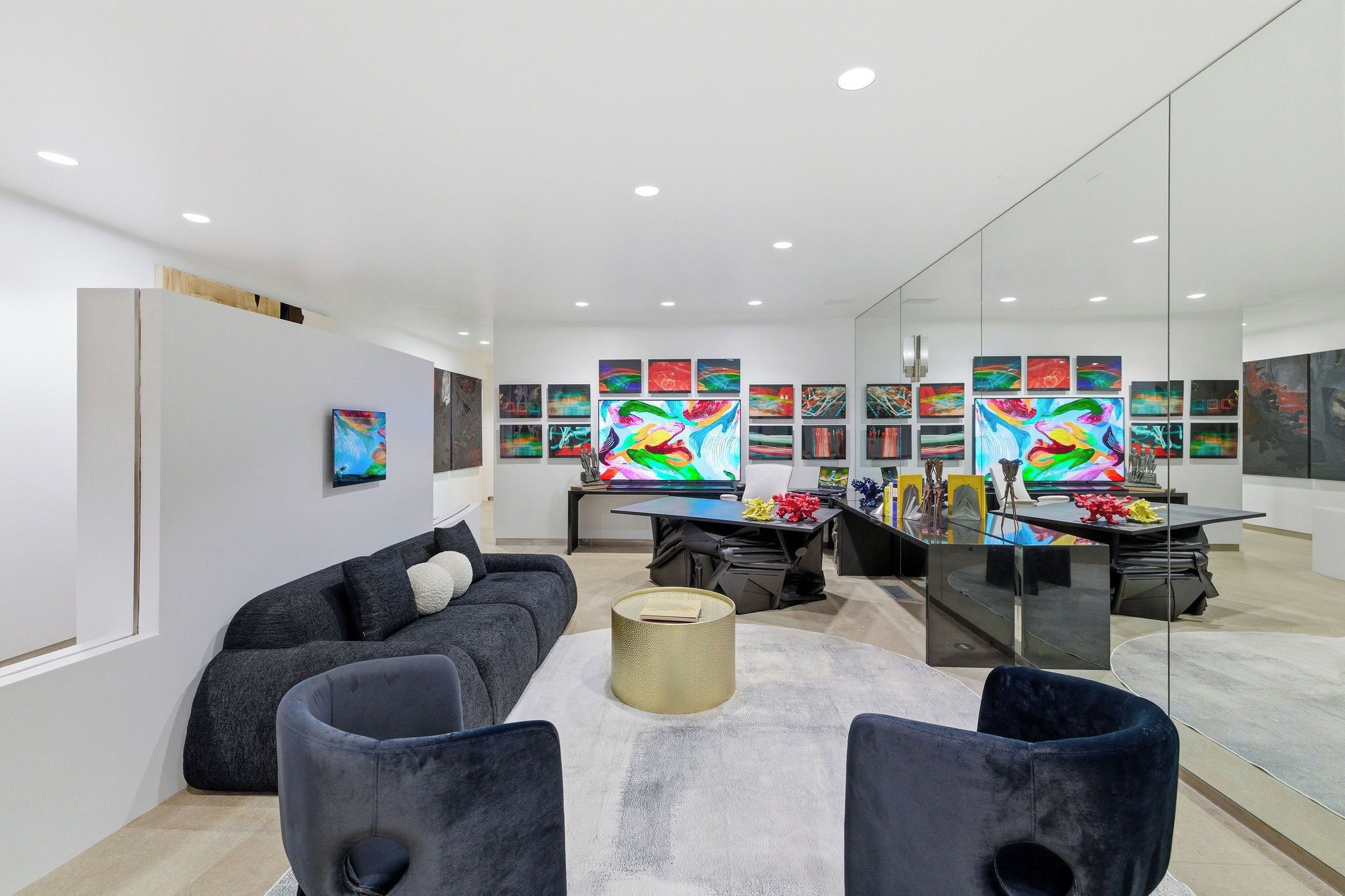A modern living room with a sofa, armchairs, a coffee table, and a desk with a computer.