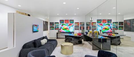 A modern living room with a sofa, armchairs, a coffee table, and a desk with a computer.