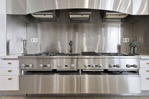 A stainless steel kitchen with multiple burners, a range hood, and built-in ovens. - Art • Architecture • A Living Masterpiece on the Hilltop of Manhattan Beach (Manhattan Beach)