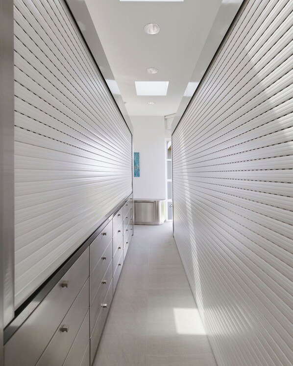 Un couloir au design moderne, avec une rangée d’armoires d’un côté et un mur orné d’un motif de l’autre.
