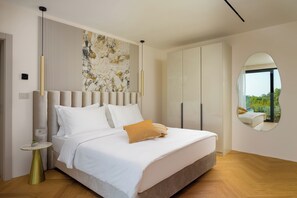 A modern bedroom with a large bed, a wall-mounted artwork, a wardrobe, and a round mirror. - Villa Terra Silentis (Istria - Pula) (Juršići)