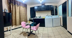 A compact kitchen with a dining area, including a table with chairs, a refrigerator, a stove, and a washing machine. - Estudiocentrico Loft, Tijuana, BC (Tijuana)