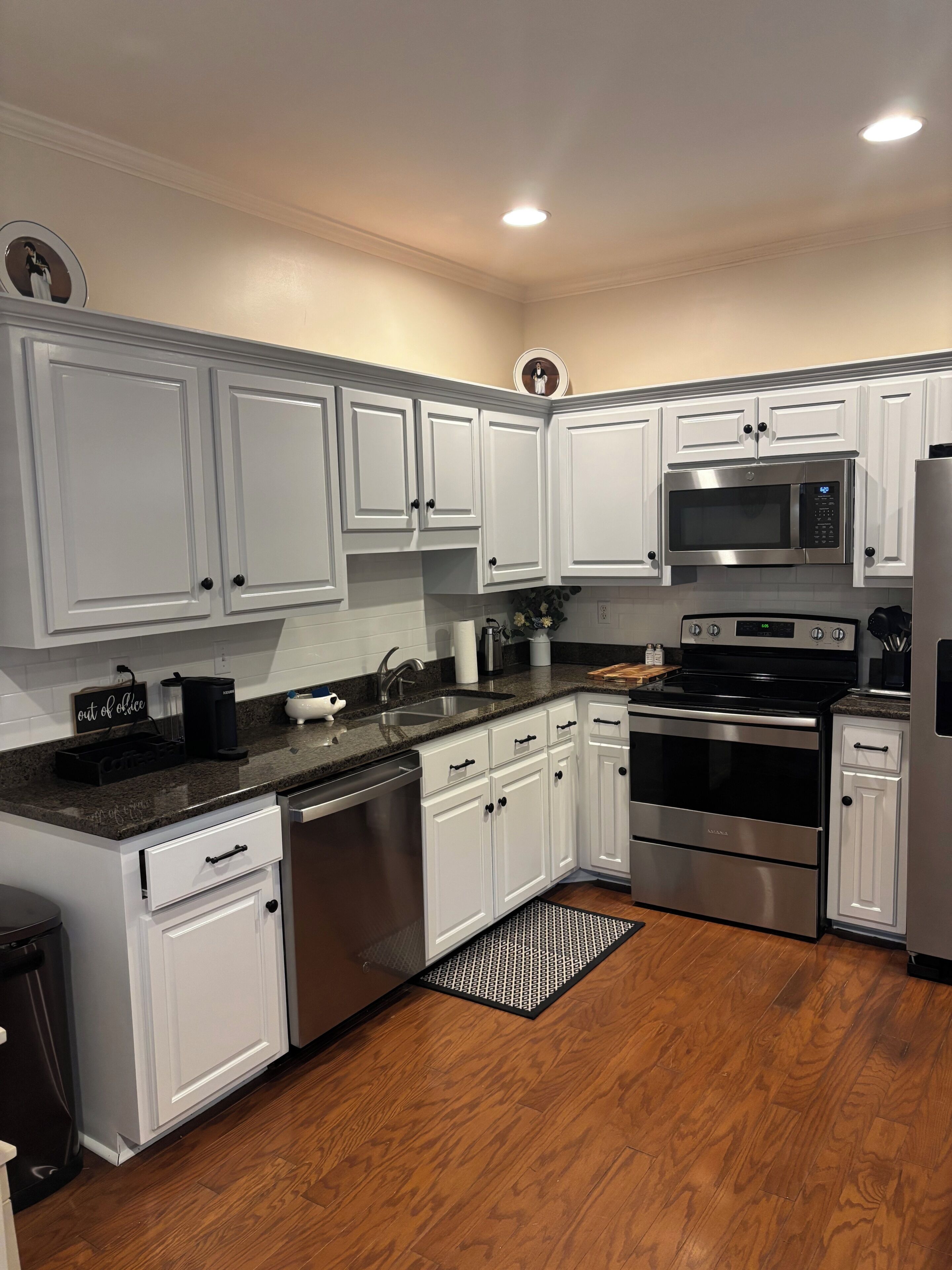 A modern kitchen with white cabinets, stainless steel appliances, and a granite countertop.