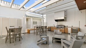 A modern outdoor kitchen with a grill, seating area, and a view of the sky. - The Perfect Old Naples Location; Walk to 5th Ave & the Beach! (Naples)