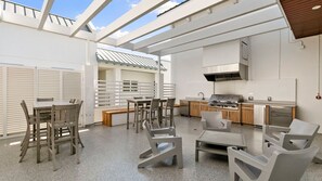 A modern outdoor kitchen with a grill, seating area, and a view of the sky. - The Perfect Old Naples Location; Walk to 5th Ave & the Beach! (Naples)