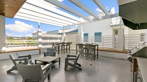 Een dakterras met buitenmeubilair, een barbecue en uitzicht op de skyline.
