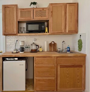 Cocina con gabinetes de madera, microondas, cafetera y pileta.