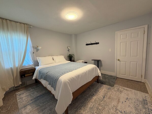 Un dormitorio con cama, mesita de noche, lámpara y una puerta.