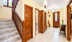 A hallway with a marble staircase, wooden doors, and a fire extinguisher on the wall. - El Joyu Erías | House with a fenced-in garden in Llanes (Vidiago)