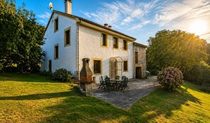 A two-story house with a patio and outdoor seating. - El Joyu Erías | House with a fenced-in garden in Llanes (Vidiago)