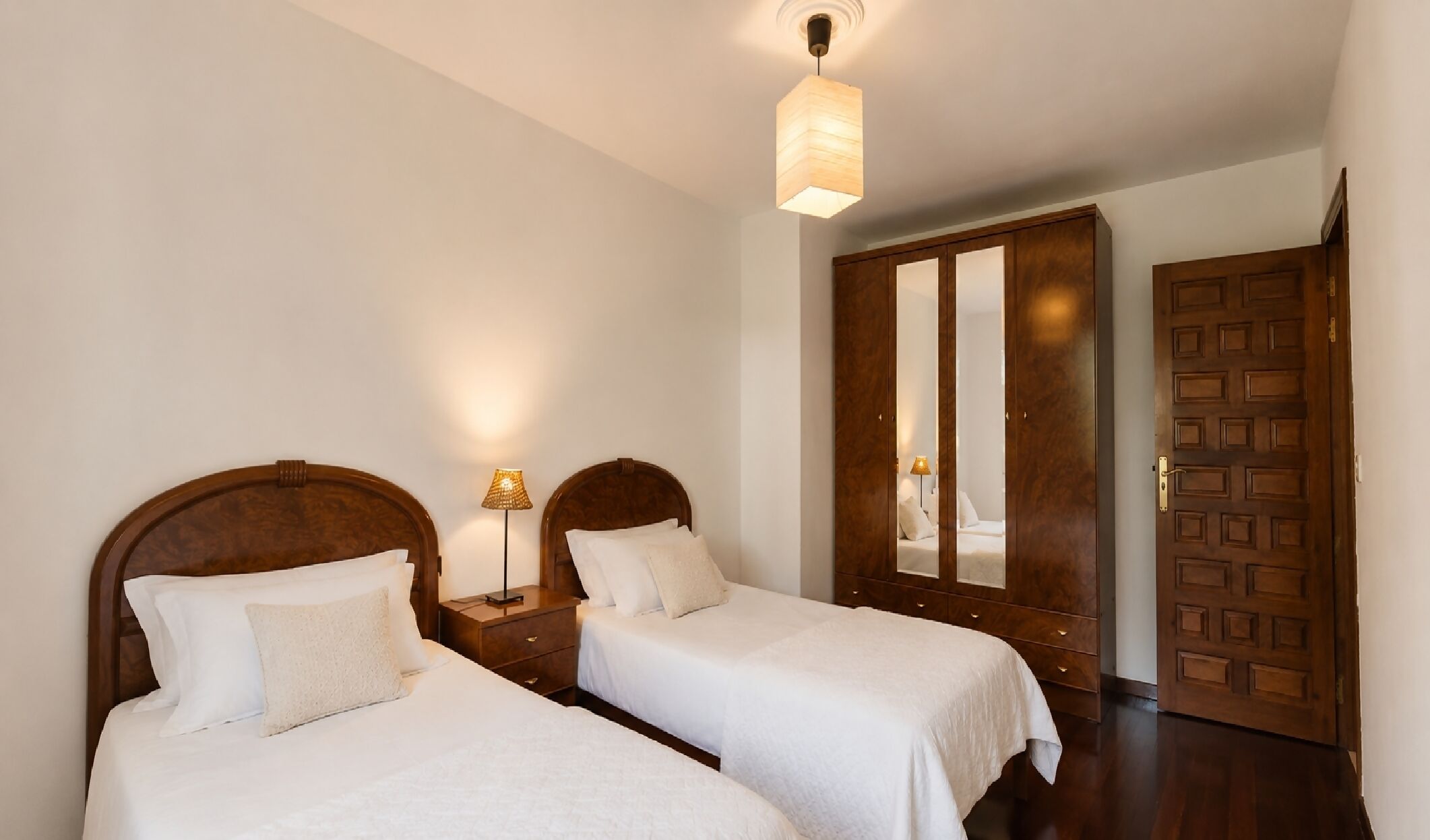 Une chambre d’hôtel avec deux lits, une armoire et un miroir.
