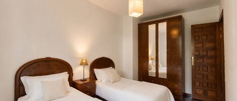 A hotel room with two beds, a wardrobe, and a mirror.