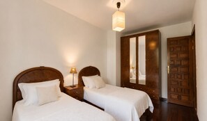 A hotel room with two beds, a wardrobe, and a mirror. - El Joyu Erías | House with a fenced-in garden in Llanes (Vidiago)