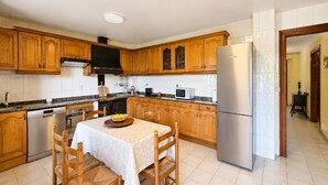 A kitchen with wooden cabinets, a stainless steel refrigerator, a microwave, and a dishwasher. - El Joyu Erías | House with a fenced-in garden in Llanes (Vidiago)