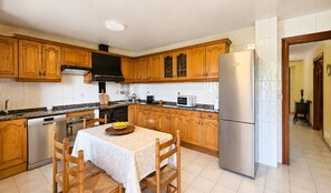 A kitchen with wooden cabinets, a stainless steel refrigerator, a microwave, and a dishwasher. - El Joyu Erías | House with a fenced-in garden in Llanes (Vidiago)