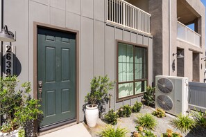 Um edifício moderno com porta verde, uma janela grande e uma varanda.
