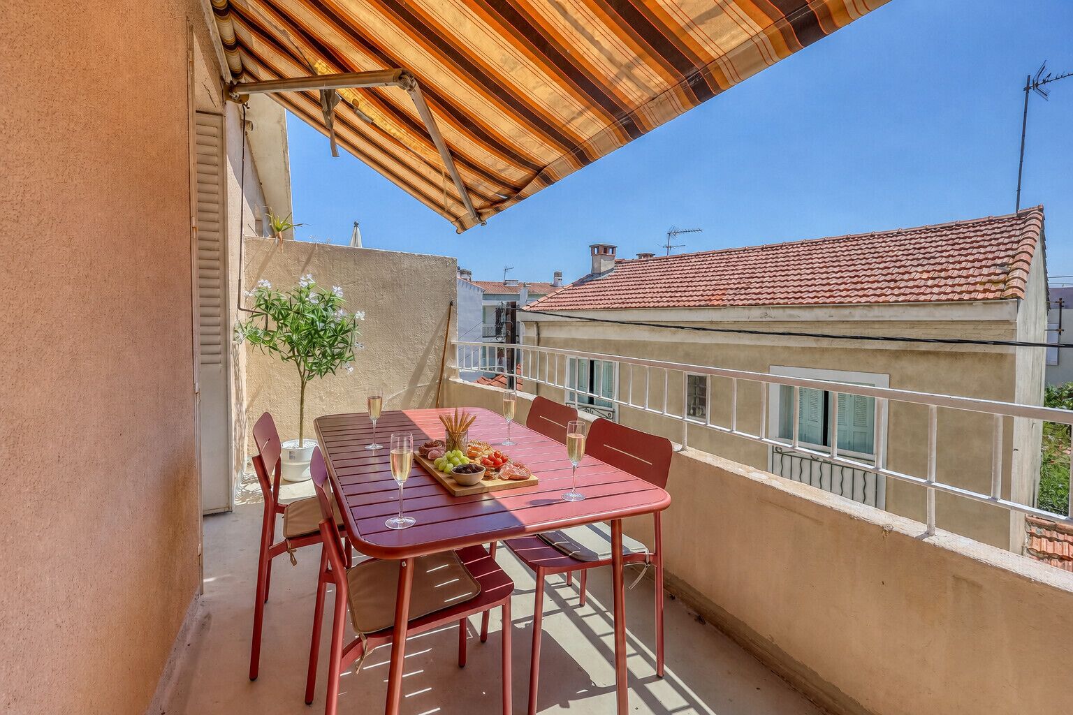 A balcony with a table set for two, featuring a glass of champagne, a fruit platter, and a bottle of wine.
