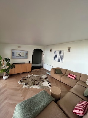 Ein Wohnzimmer mit einer Couch, einem Couchtisch, einer Topfpflanze und einem Teppich.