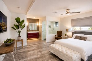 Ein modernes Schlafzimmer mit einem großen Bett, einer Sitzecke mit einem Sessel, einem kleinen Tisch und einer Topfpflanze.