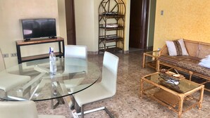 A living room with a glass table, chairs, a sofa, a television, and a wicker chair. - AriCo is your home away from home in Cochabamba. 🏡 (Cochabamba)