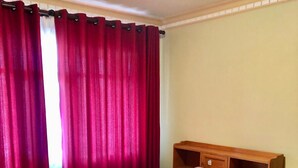 A single bed with a wooden headboard, a bedside table, and a red curtain. - AriCo is your home away from home in Cochabamba. 🏡 (Cochabamba)