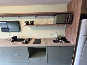 Eine moderne Küche mit Flachbildfernseher, Mikrowelle und Kühlschrank.