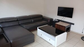 Un soggiorno moderno con un divano componibile, un tavolino da caffè e una televisione a schermo piatto montata a parete.