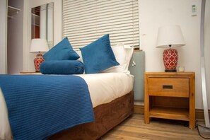 Una camera da letto con un letto, un comodino, una lampada e uno specchio.