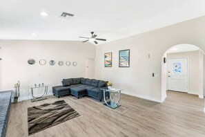 A modern living room with a sectional sofa, a glass coffee table, and a decorative rug. - Sun-Drenched Vegas Retreat w/ Pool & Huge Yard (North Las Vegas)