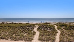 A beach path leading to the ocean with dunes and beach umbrellas. - Oceanfront, Bottom Floor condo with pool, balcony, washer/dryer (Fernandina Beach)