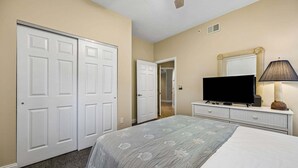 A hotel room with a bed, a television, a dresser, and a closet. - Oceanfront, Bottom Floor condo with pool, balcony, washer/dryer (Fernandina Beach)